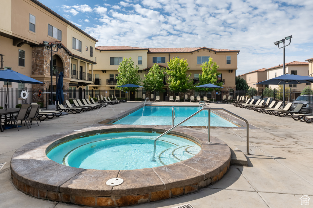 View of swimming pool featuring a patio and a hot tub