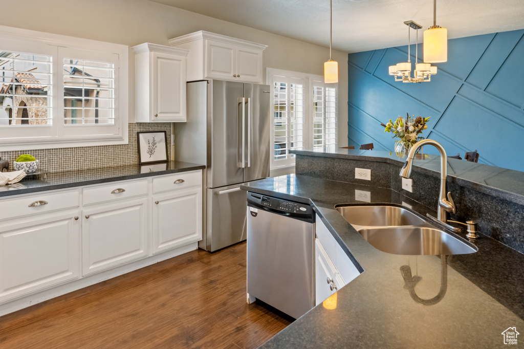 Kitchen featuring white cabinets, sink, dark hardwood / wood-style floors, appliances with stainless steel finishes, and backsplash