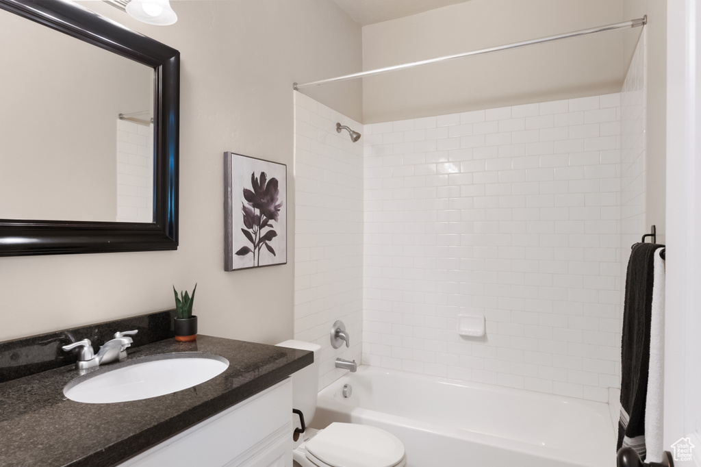 Full bathroom featuring vanity, tiled shower / bath combo, and toilet