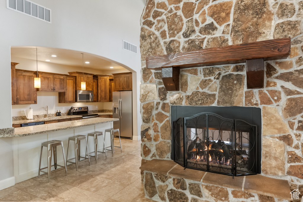 Room details featuring sink, tile patterned floors, a fireplace, and stainless steel appliances