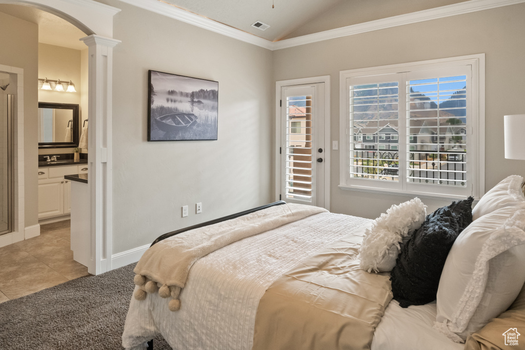 Bedroom with decorative columns, lofted ceiling, ornamental molding, and light tile patterned floors