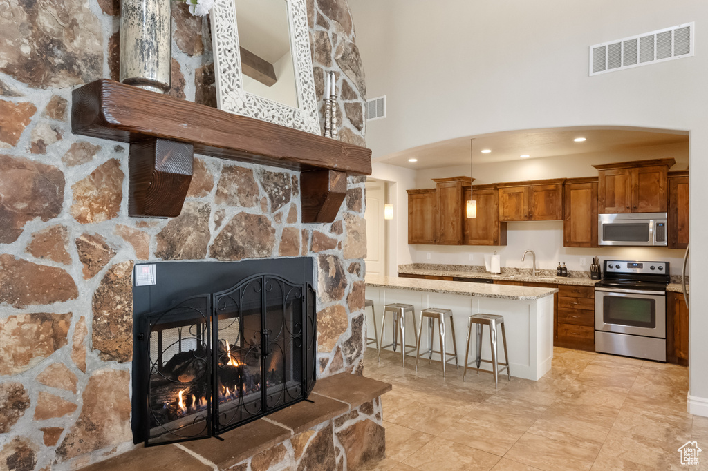 Kitchen with stainless steel appliances, a breakfast bar, sink, a fireplace, and light tile patterned flooring