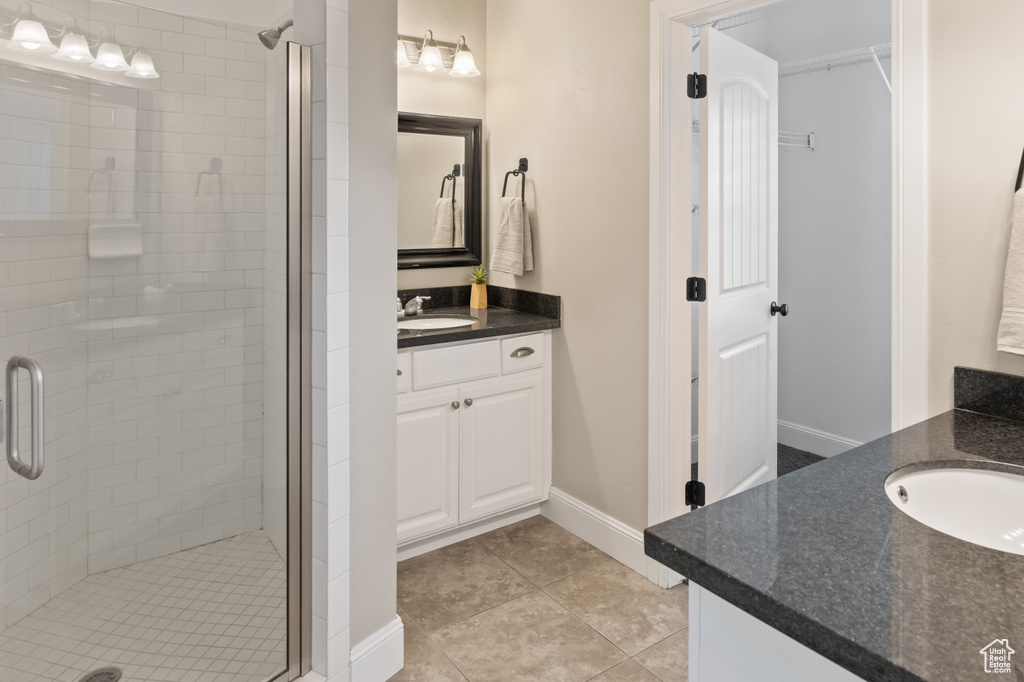 Bathroom featuring tile patterned flooring, a shower with door, and vanity