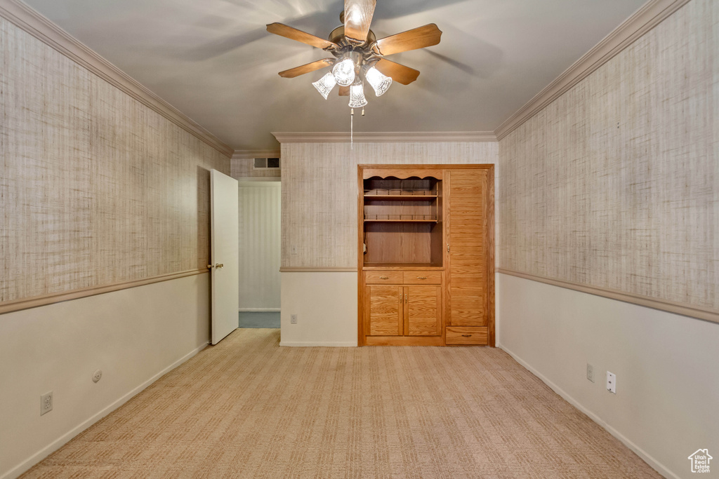 Carpeted spare room with crown molding and ceiling fan