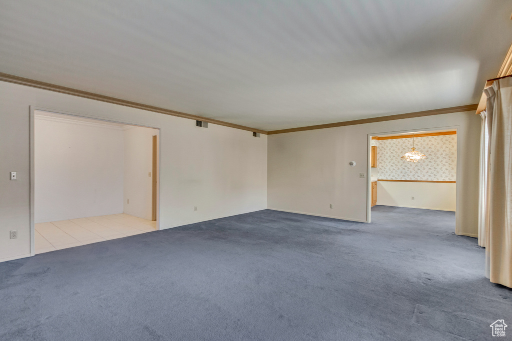 Carpeted empty room with an inviting chandelier and crown molding