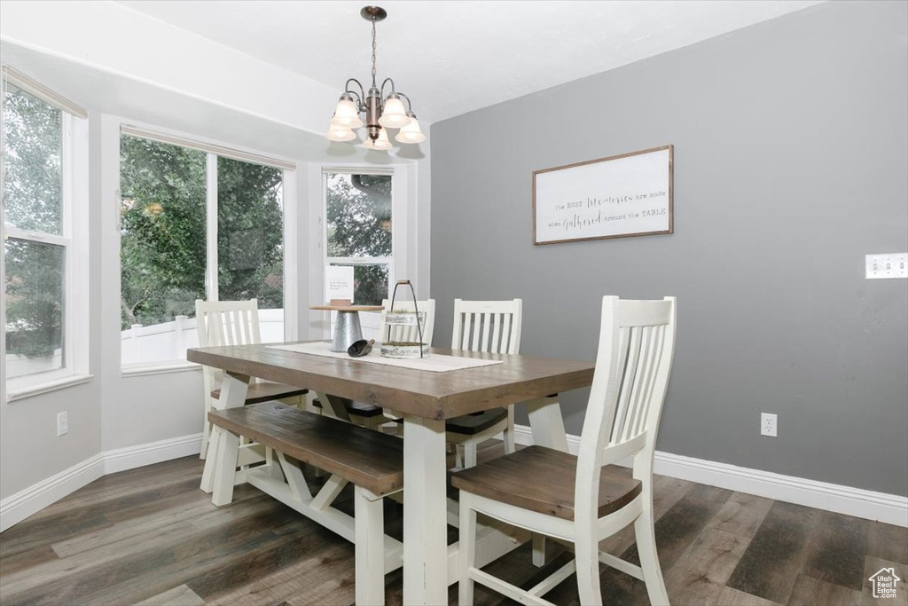 Dining space with dark hardwood / wood-style floors, a healthy amount of sunlight, and an inviting chandelier