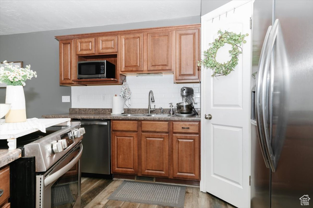 Kitchen featuring sink, dark wood-type flooring, tasteful backsplash, and stainless steel appliances