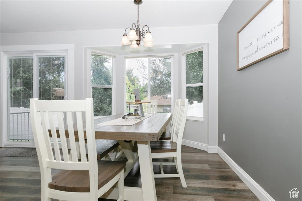 Dining area with dark wood-type flooring and a chandelier