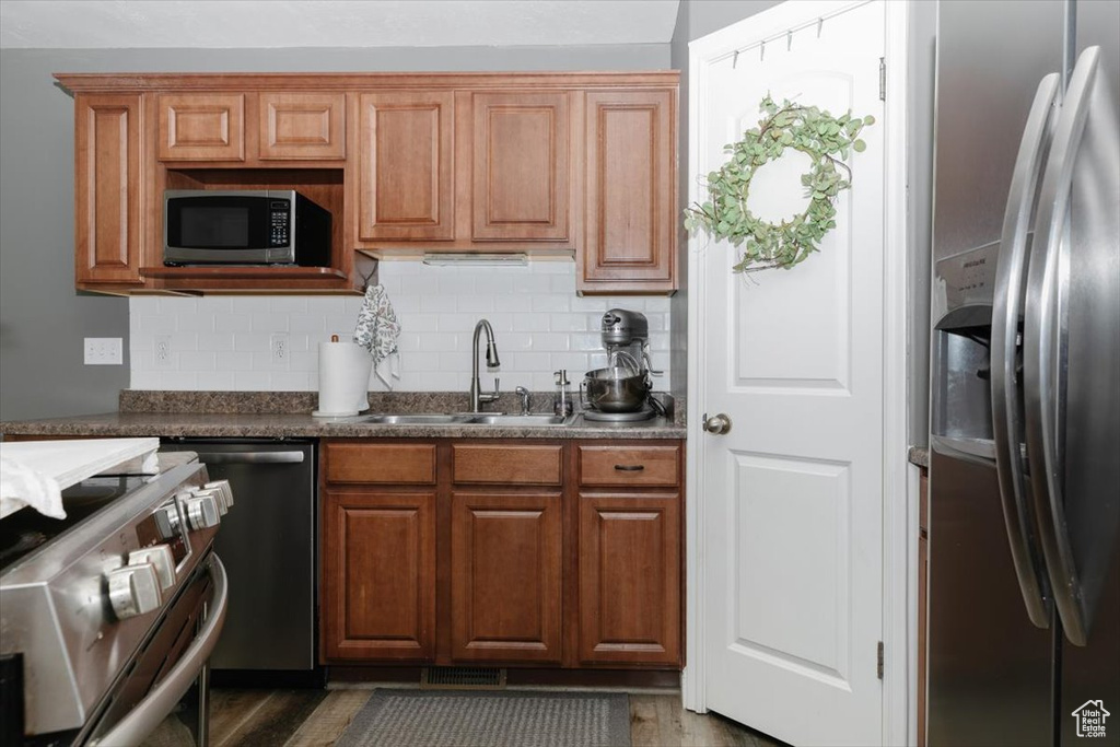 Kitchen featuring sink, appliances with stainless steel finishes, tasteful backsplash, and hardwood / wood-style floors