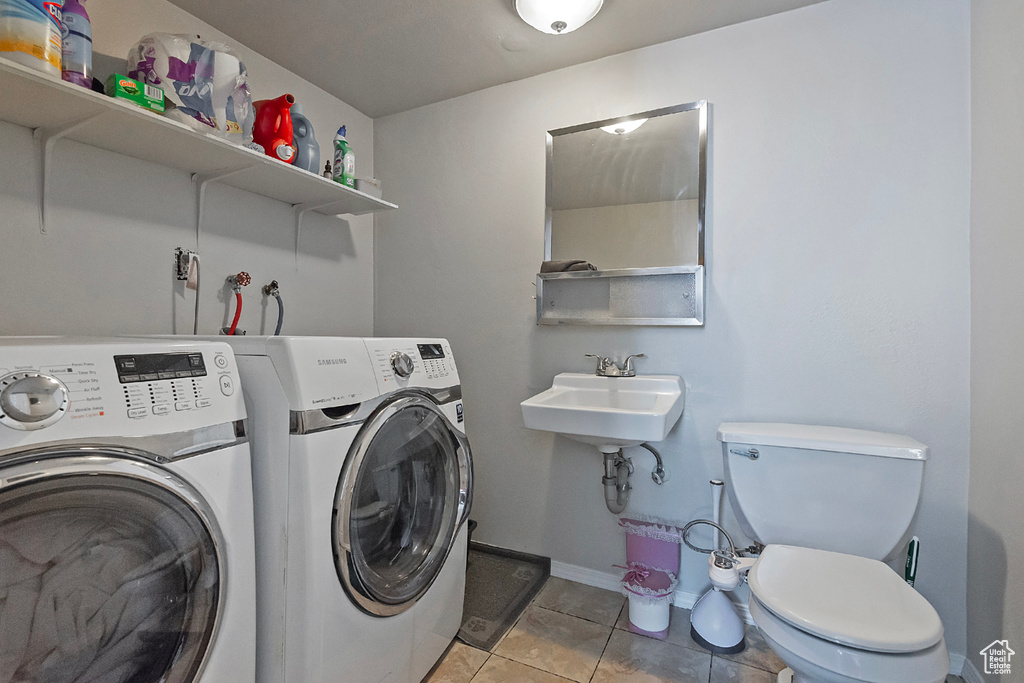 Clothes washing area featuring light tile patterned flooring and independent washer and dryer