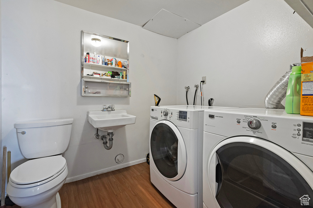 Washroom with sink, washer and dryer, and dark hardwood / wood-style floors