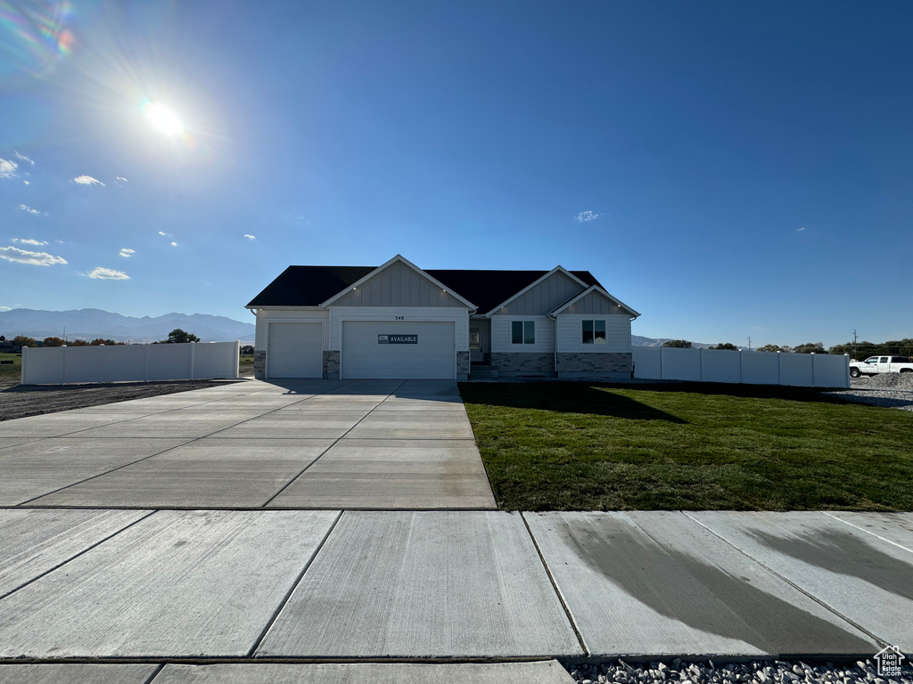 View of front of house featuring a garage, a front yard, and a mountain view