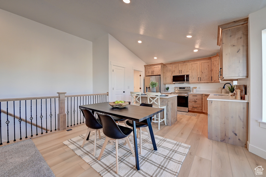 Dining space with lofted ceiling, light hardwood / wood-style flooring, and sink