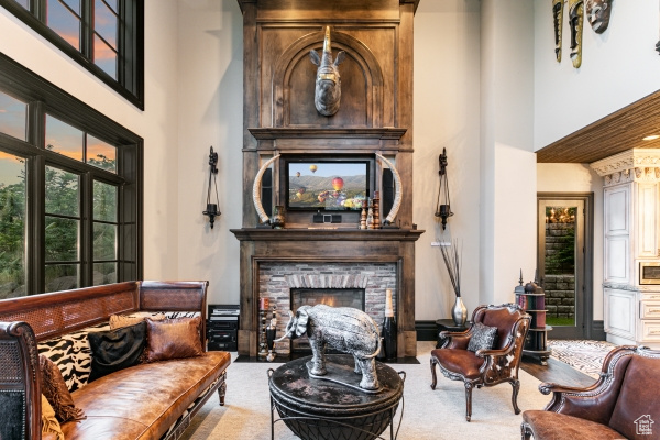 Sitting room with carpet, a stone fireplace, and a high ceiling