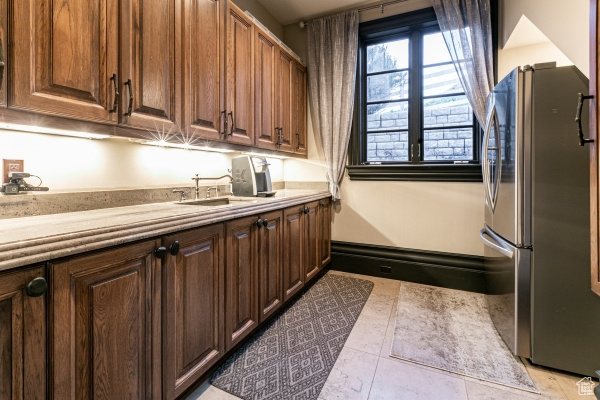 Kitchen with stainless steel fridge, sink, and light tile patterned flooring