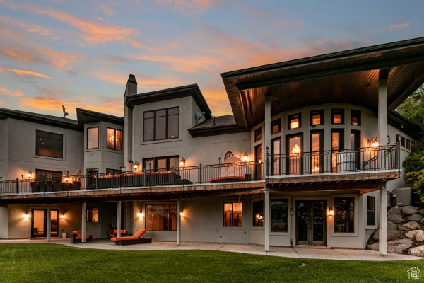 Back house at dusk with a yard, a balcony, and a patio area