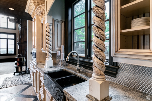 Kitchen with light tile patterned flooring, stone countertops, a wealth of natural light, and sink