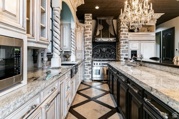 Kitchen with light tile patterned flooring, stainless steel microwave, light stone counters, and wooden ceiling