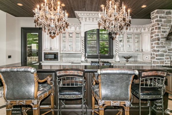 Bar with stainless steel microwave, plenty of natural light, and wood ceiling