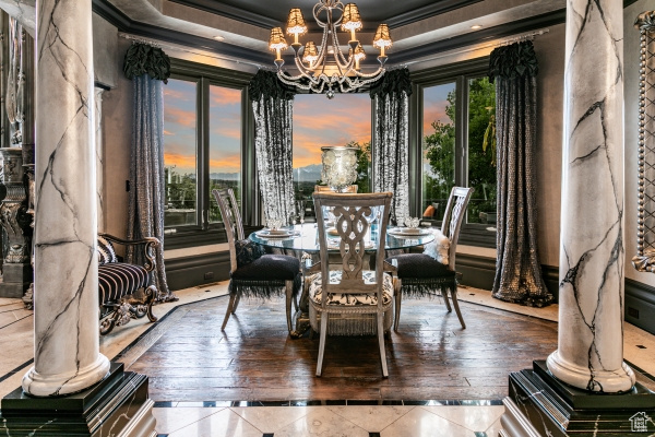 Dining room with an inviting chandelier, crown molding, hardwood / wood-style flooring, and a raised ceiling