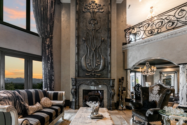 Living room with a fireplace, a chandelier, ornamental molding, and a towering ceiling