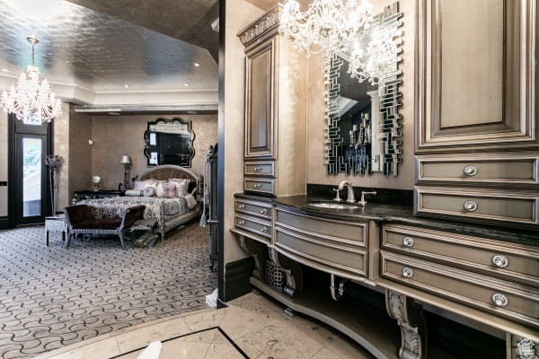 Bedroom featuring sink, a tray ceiling, a notable chandelier, and light tile patterned floors