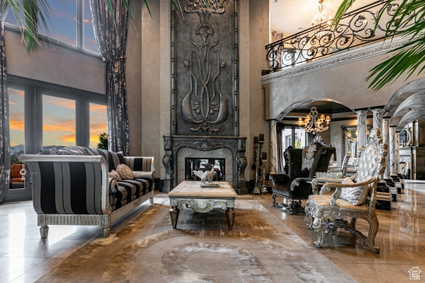 Interior space featuring tile patterned flooring, decorative columns, an inviting chandelier, a premium fireplace, and a towering ceiling