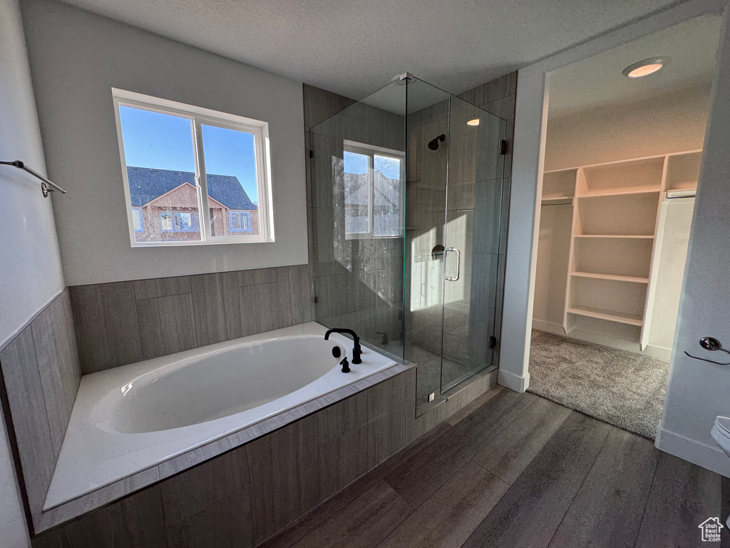 Bathroom with a textured ceiling, hardwood / wood-style flooring, and plus walk in shower