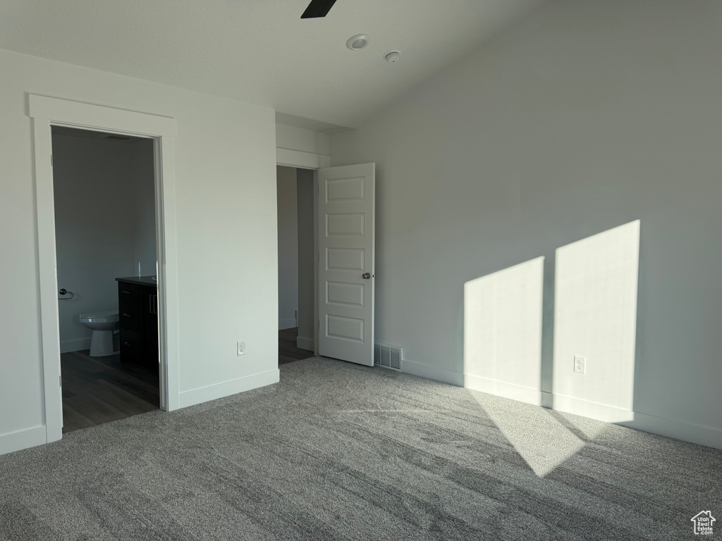 Unfurnished bedroom with ensuite bathroom, ceiling fan, and carpet flooring