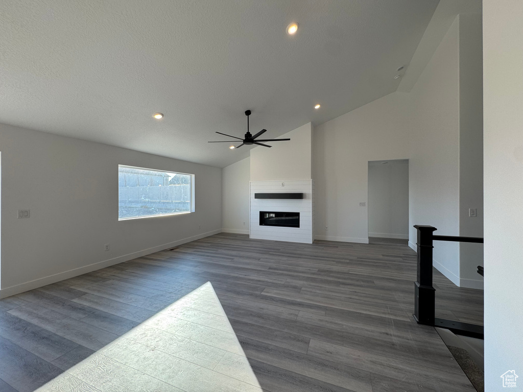 Unfurnished living room with high vaulted ceiling, ceiling fan, and wood-type flooring