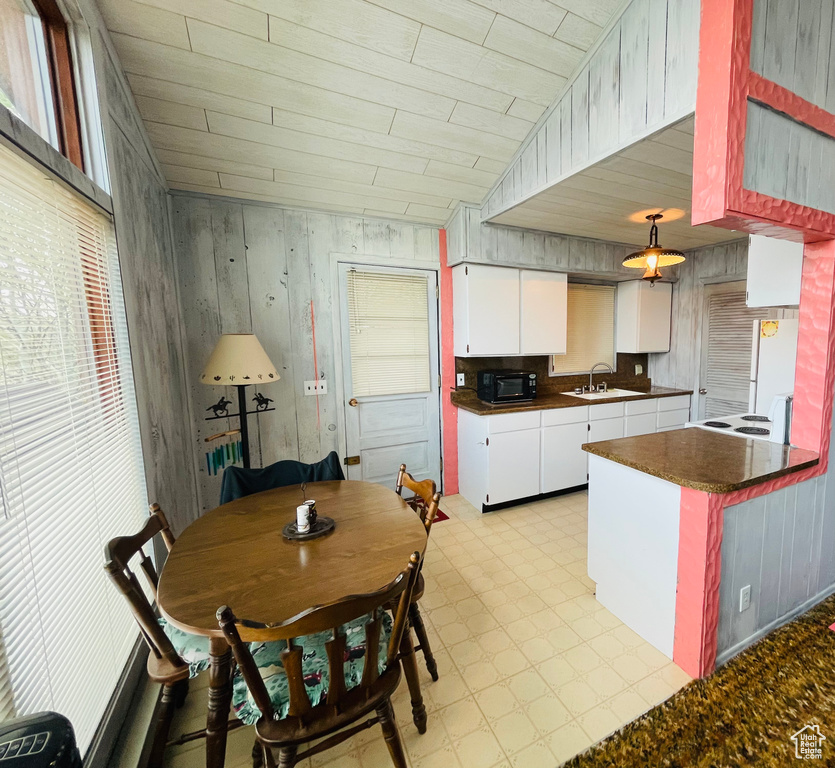 Kitchen with hanging light fixtures, sink, light tile patterned floors, and white cabinets