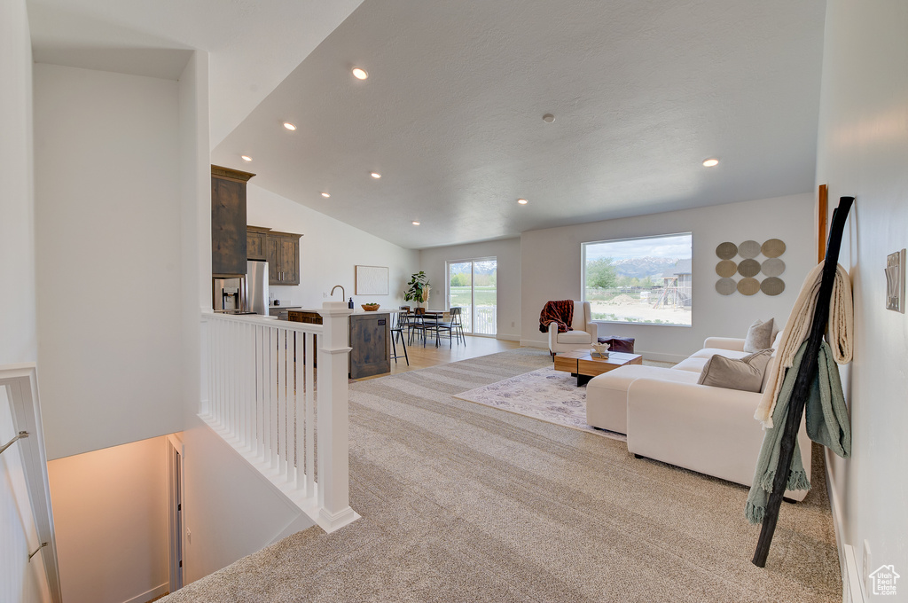 Carpeted living room with vaulted ceiling and sink