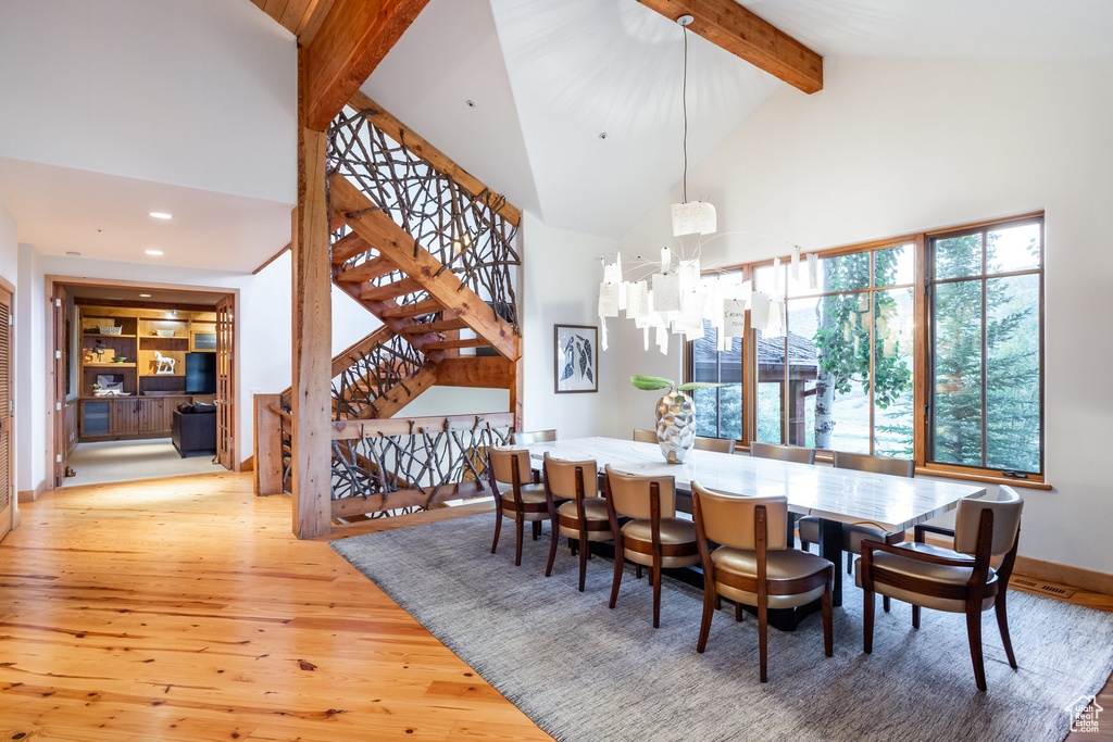 Dining area featuring an inviting chandelier, beamed ceiling, light hardwood / wood-style floors, and high vaulted ceiling