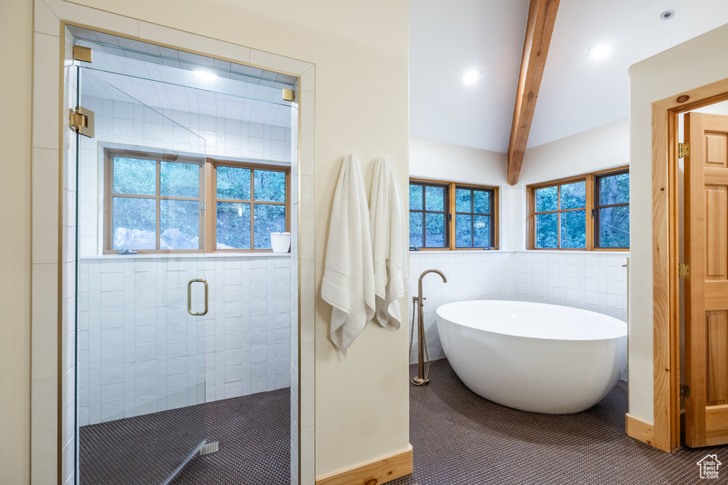 Bathroom featuring beamed ceiling, separate shower and tub, a healthy amount of sunlight, and tile walls