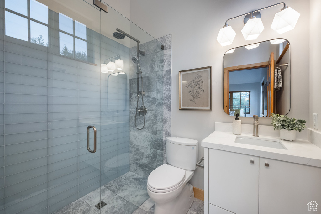 Bathroom featuring a shower with door, vanity, tile patterned flooring, and toilet