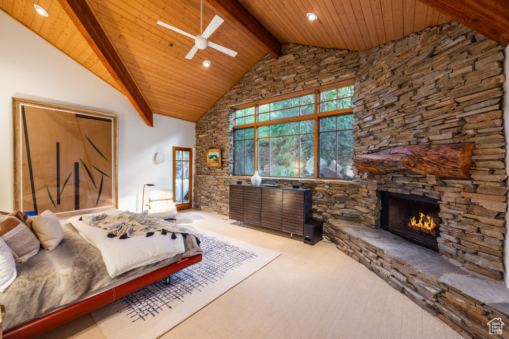 Bedroom with a stone fireplace, beamed ceiling, carpet floors, and high vaulted ceiling