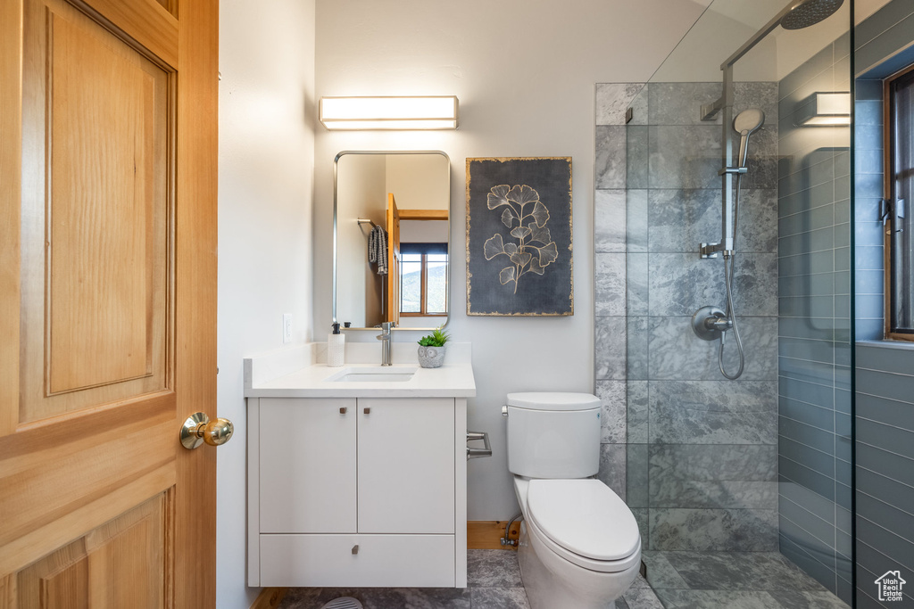 Bathroom with vanity, tile patterned floors, a tile shower, and toilet