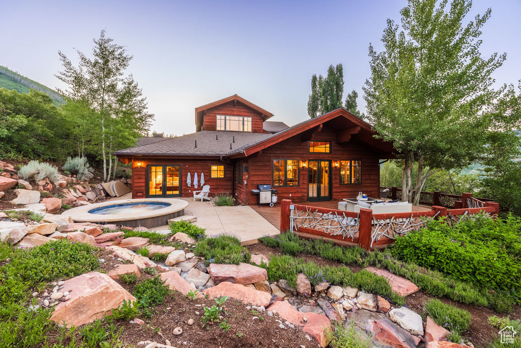 Rear view of property with a patio area, an in ground hot tub, and a wooden deck