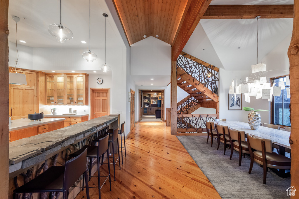 Dining area with light hardwood / wood-style floors, a notable chandelier, and high vaulted ceiling