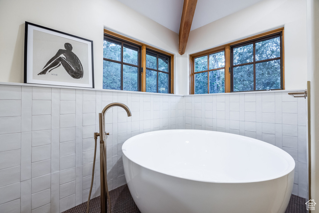 Bathroom with beam ceiling, tile walls, and plenty of natural light