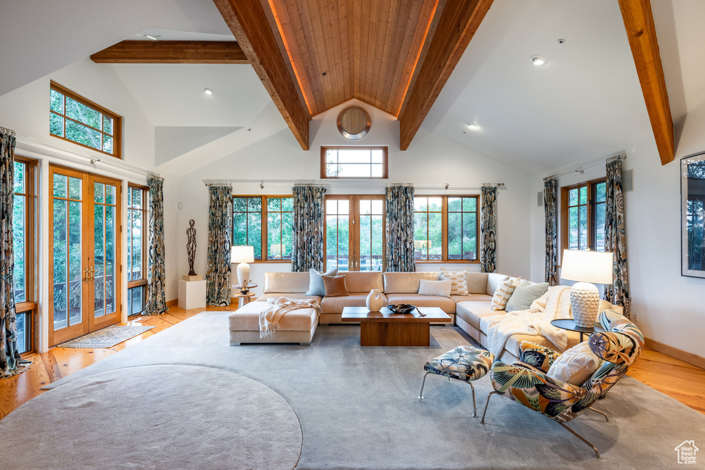 Living room with high vaulted ceiling, beamed ceiling, french doors, and light hardwood / wood-style flooring