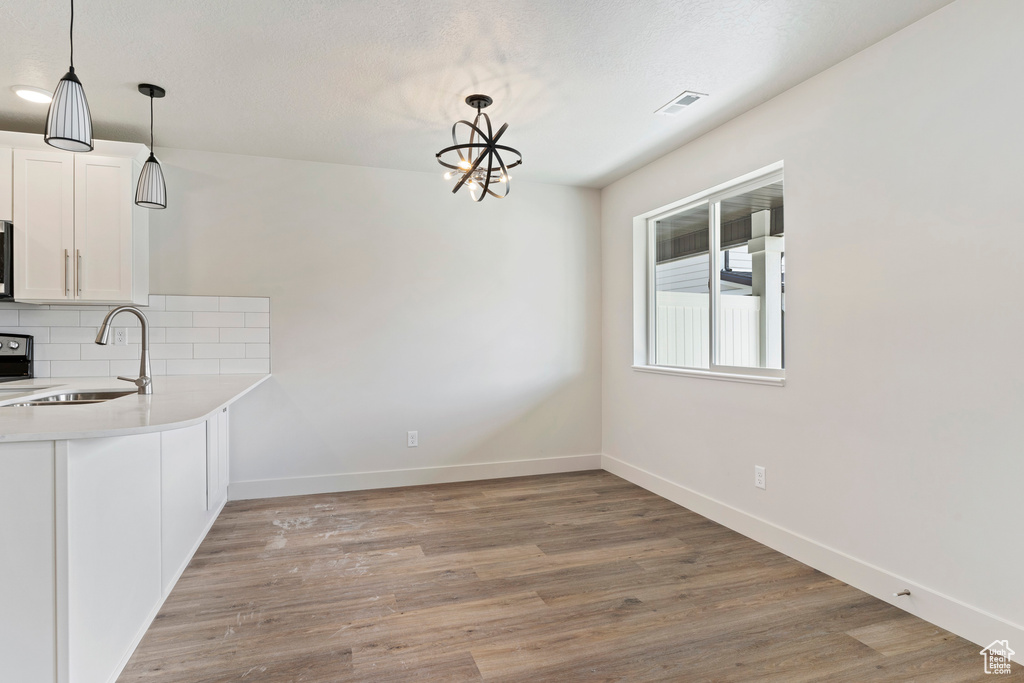 Unfurnished dining area featuring light hardwood / wood-style floors, sink, and an inviting chandelier