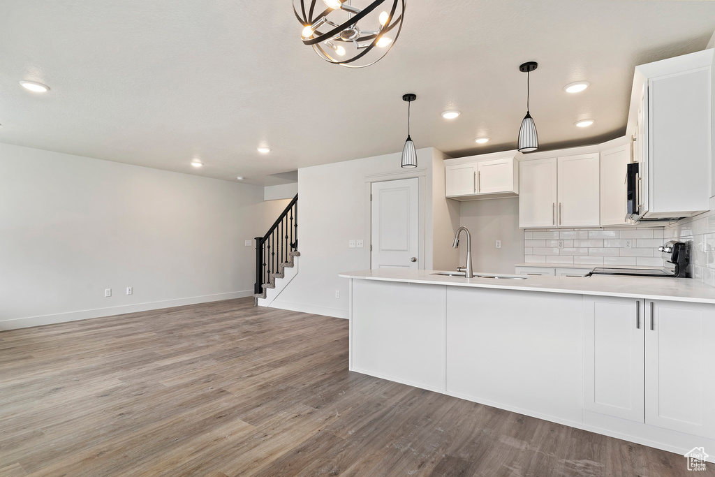 Kitchen with hanging light fixtures, range, decorative backsplash, sink, and light hardwood / wood-style flooring