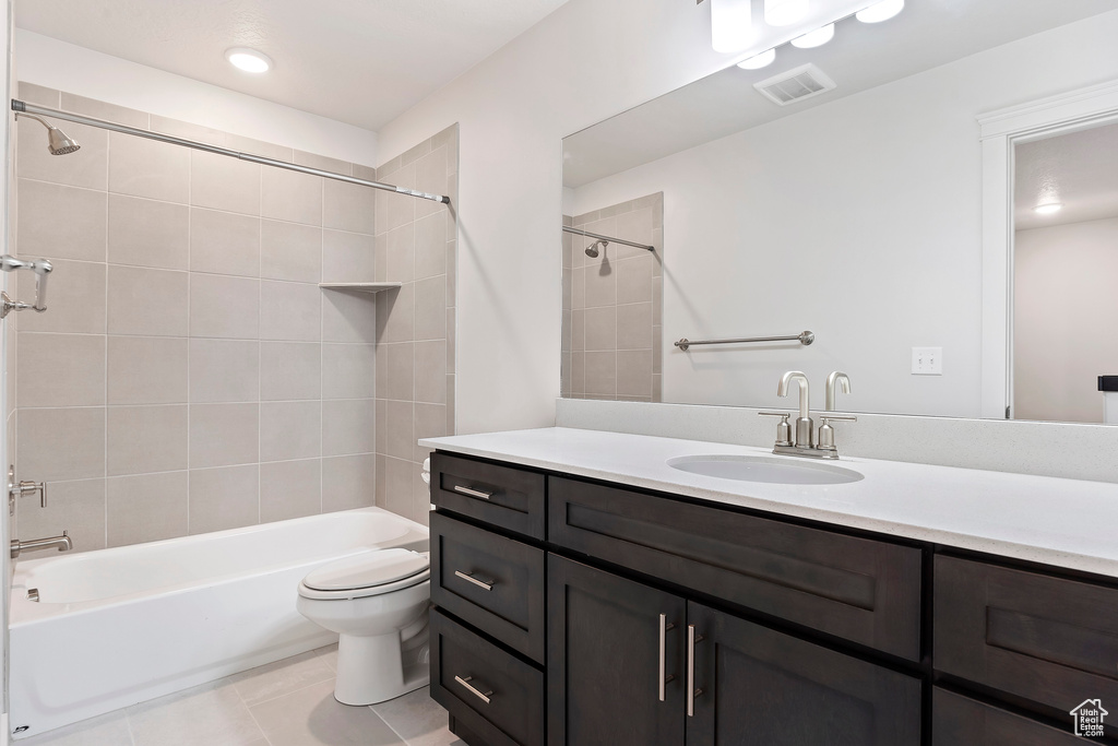 Full bathroom featuring vanity, tile patterned flooring, tiled shower / bath combo, and toilet