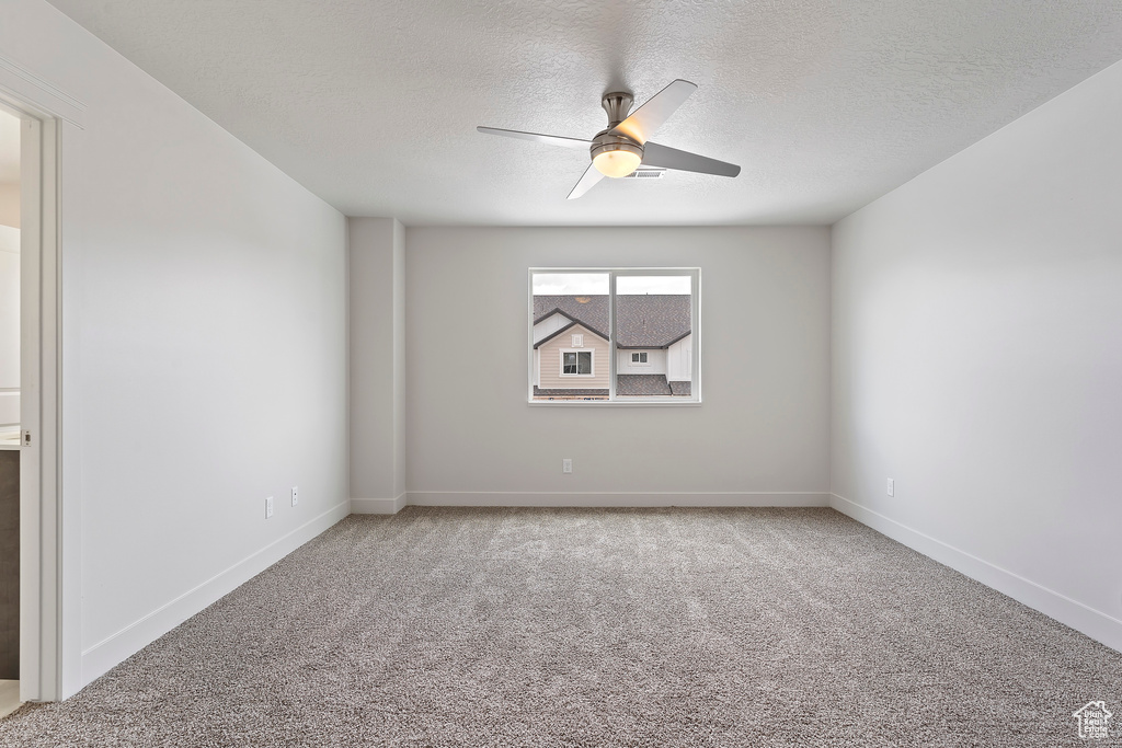 Carpeted spare room with a textured ceiling and ceiling fan