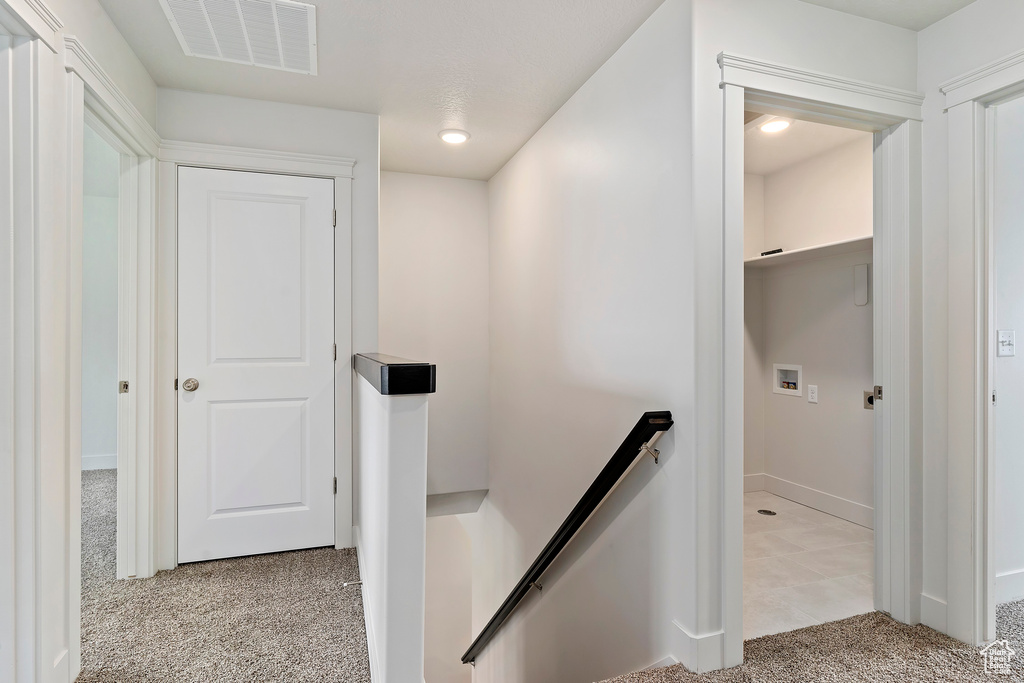 Hallway featuring light colored carpet