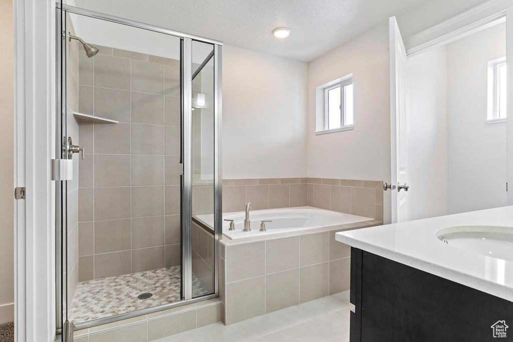 Bathroom with tile patterned floors, plus walk in shower, vanity, and a textured ceiling