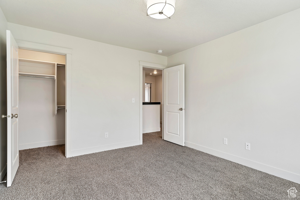 Unfurnished bedroom with carpet floors, a walk in closet, and a closet