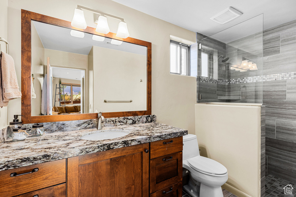 Bathroom with vanity, toilet, and tiled shower