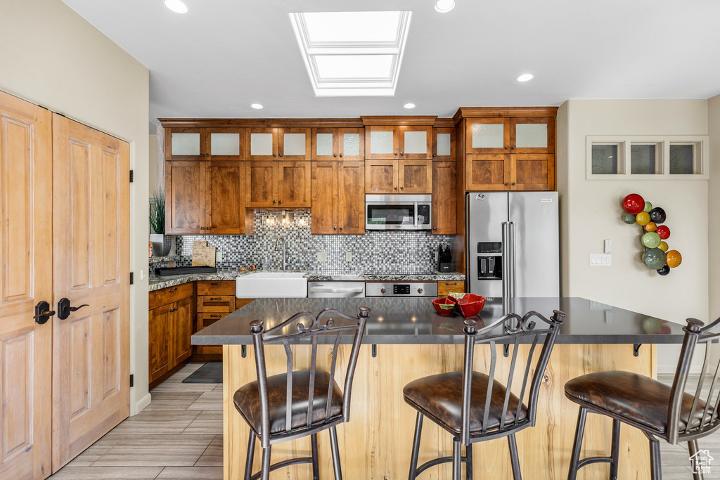 Kitchen featuring sink, a kitchen island, a kitchen bar, and stainless steel appliances